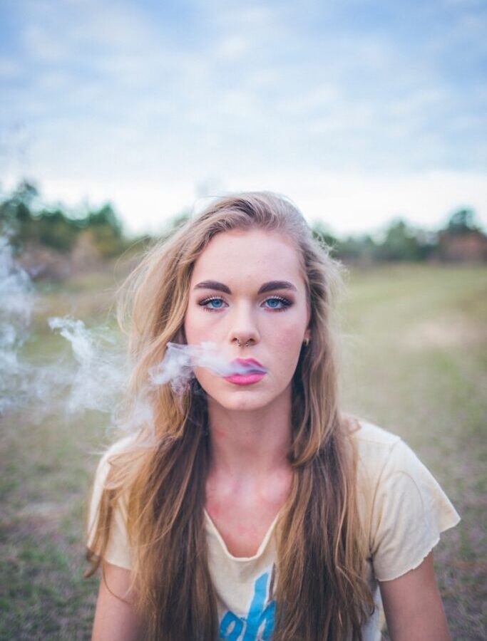 woman smoking while sitting on green grass