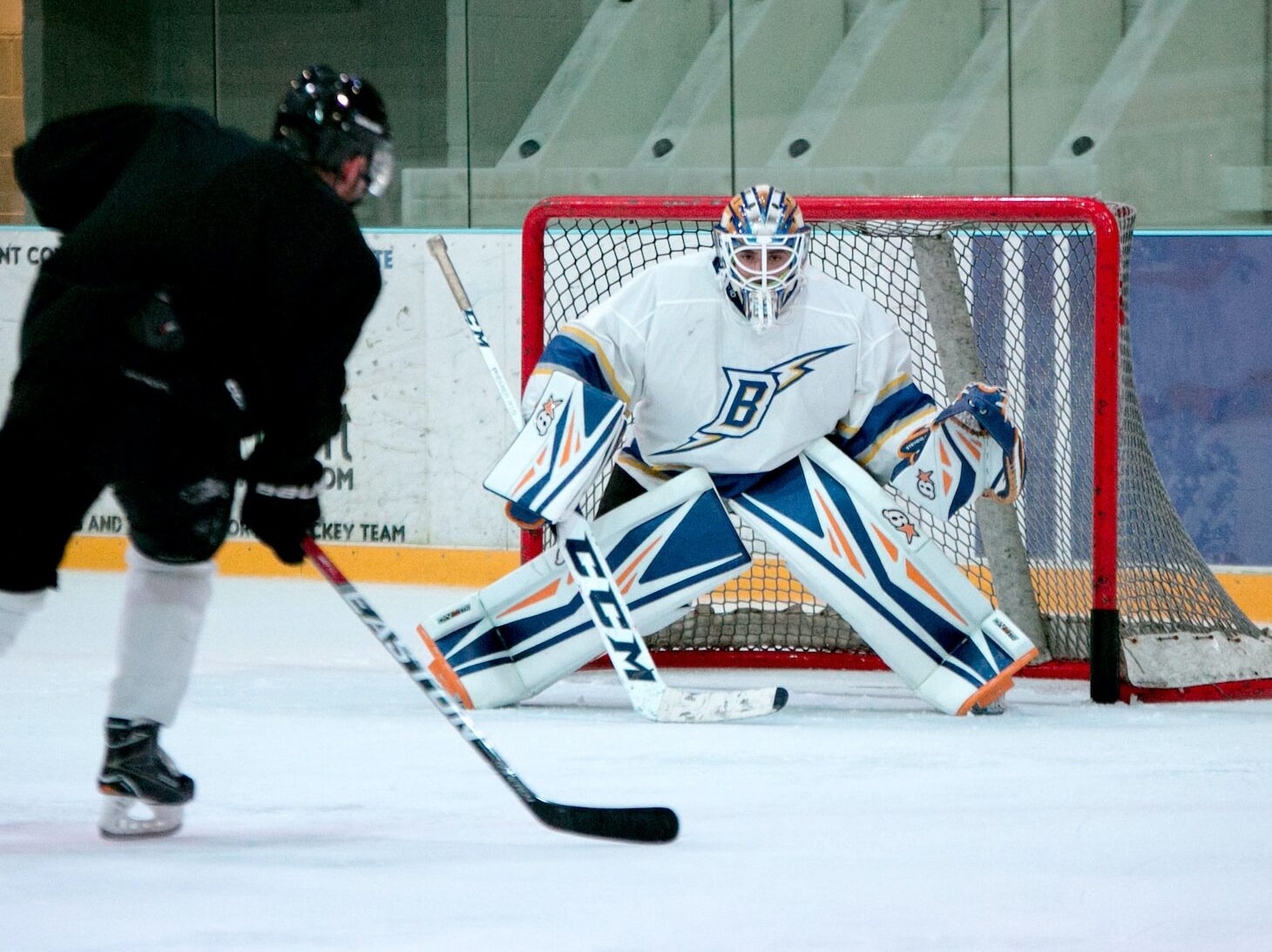 man taking aim for goal on hockey goalie