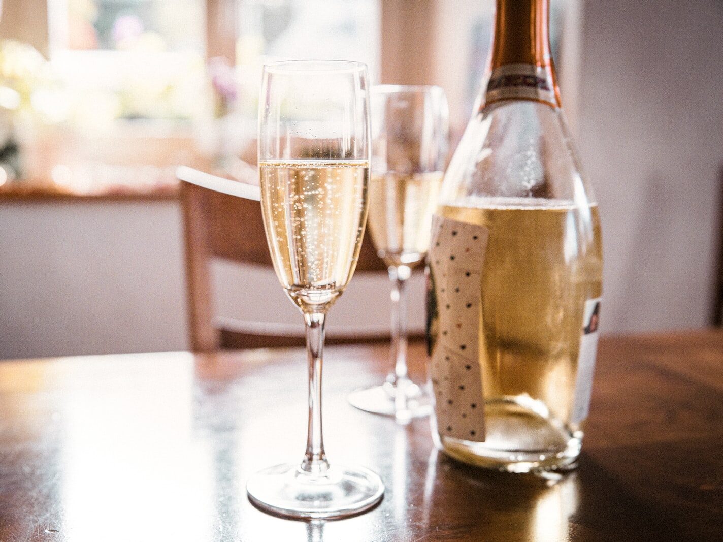 clear wine glass beside clear glass bottle on brown wooden table