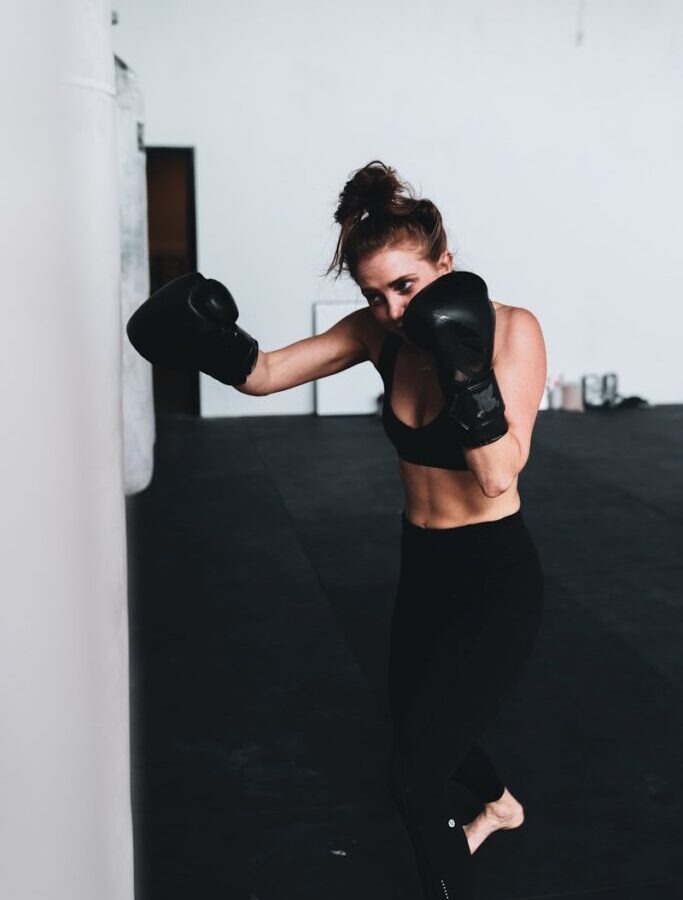 woman in black sports bra and black leggings wearing black boxing gloves