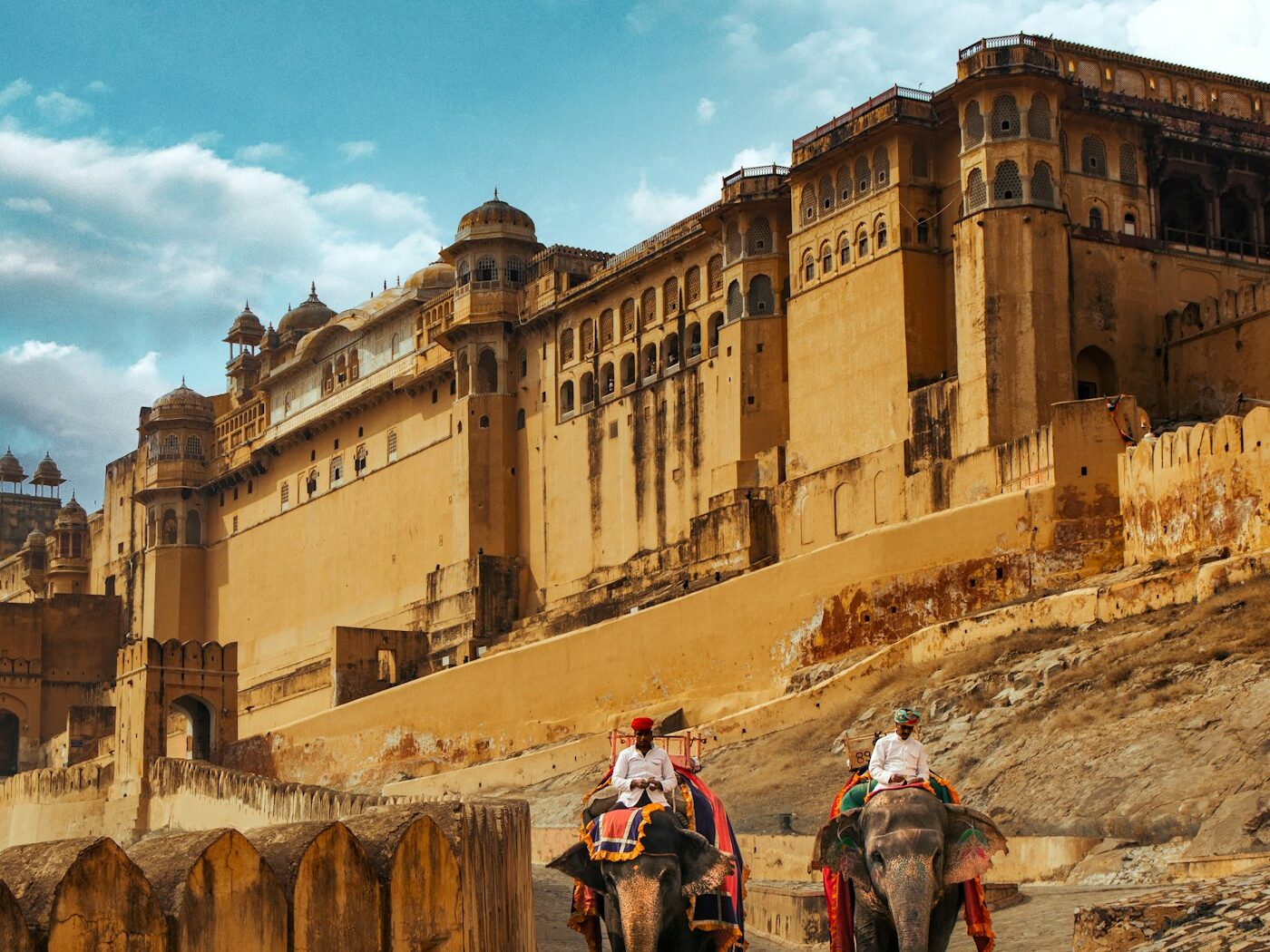 two people riding on the backs of elephants