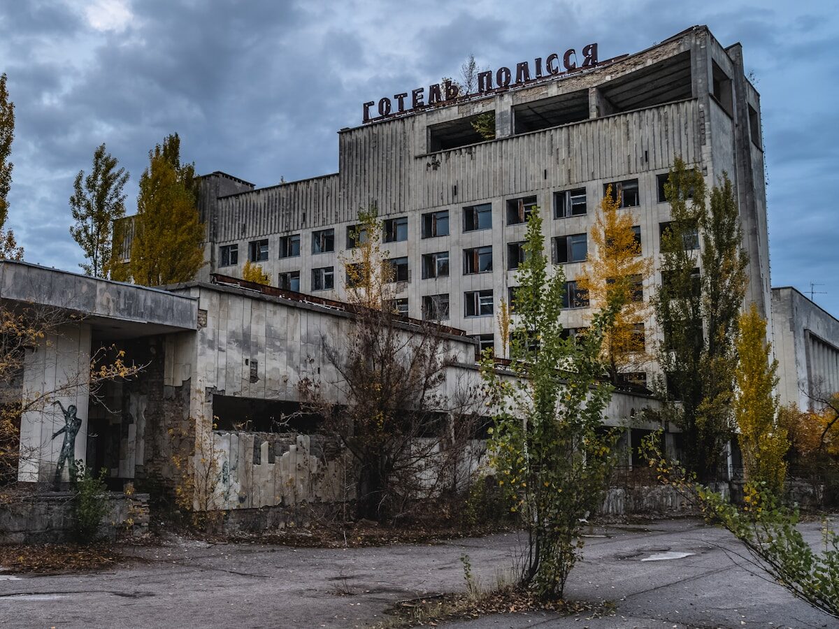 white concrete building near green trees under white clouds during daytime