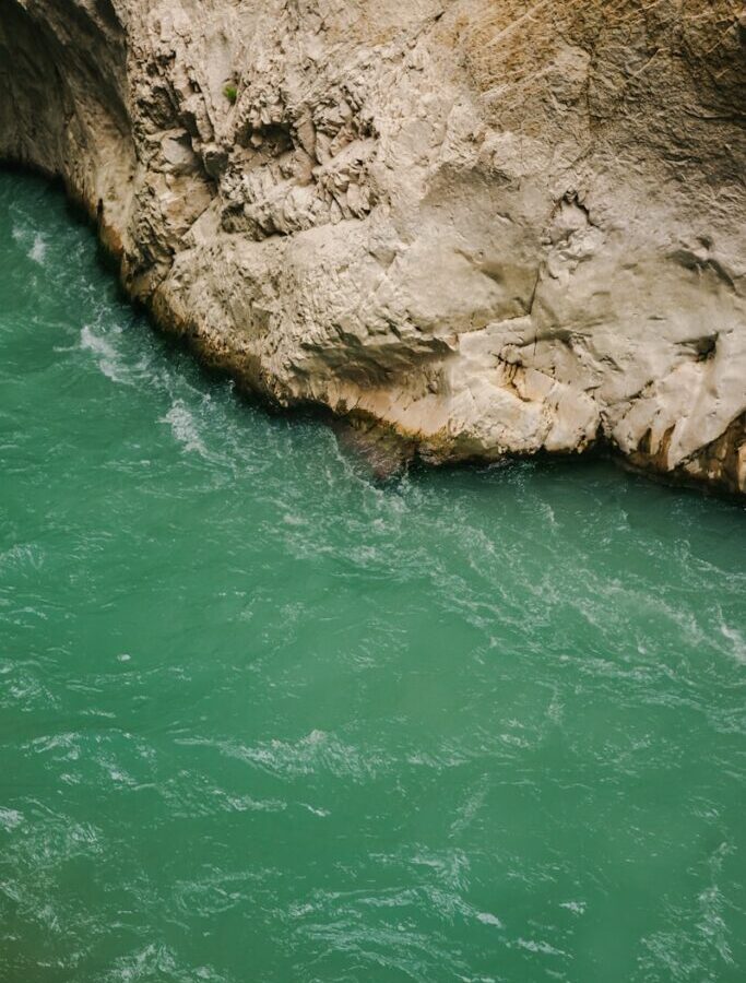 a man in a kayak in the water next to a cliff