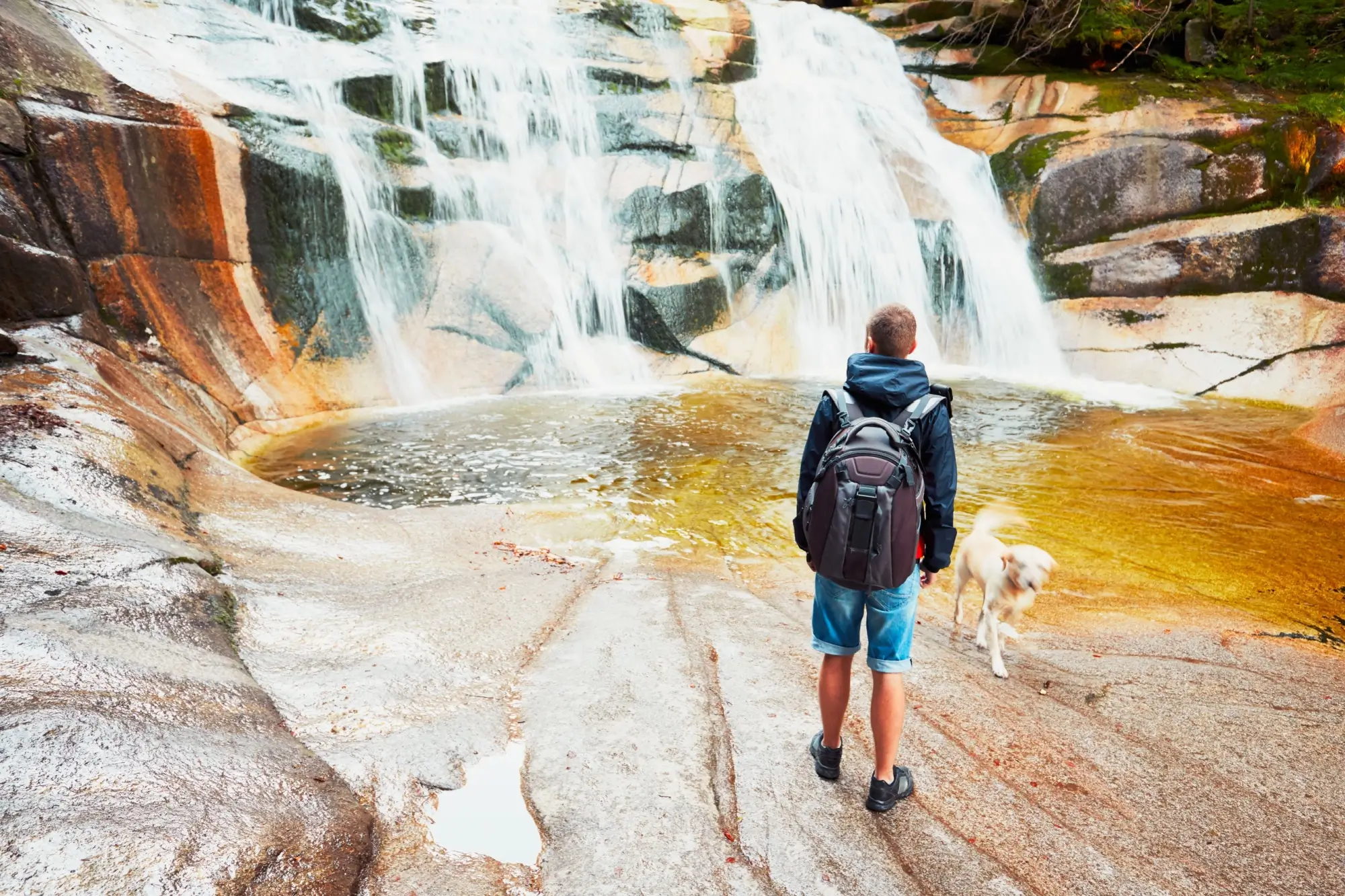 Mumlavský vodopád s turistou a psem.