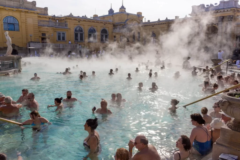 Termální lázně Széchenyi v Budapešti pod širým nebem s relaxujícími lidmi za slunečného dne